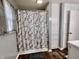 Bathroom with gray and white shower curtain, wood floor, cabinets and window at 1579 Crest Dr, Shelbyville, IN 46176