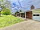 Side view of brick home showing front yard, covered porch, and attached two car garage at 1579 Crest Dr, Shelbyville, IN 46176