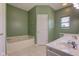 Bathroom with a tub, double sinks, green walls, tile flooring and natural lighting through a window at 2234 Burgundy Way, Plainfield, IN 46168