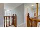 Upstairs hallway featuring wooden railing, views of downstairs, an open door, and wall lighting at 2234 Burgundy Way, Plainfield, IN 46168