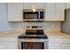 Stainless steel microwave, oven and cooktop with white cabinets and countertops in modern kitchen at 2234 Burgundy Way, Plainfield, IN 46168