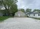 Charming single-story home with a large gravel driveway and a cozy front porch, enveloped by lush trees at 2608 S Rybolt Ave, Indianapolis, IN 46241