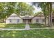 Charming stone home featuring mature trees, manicured lawn and a traditional American flag display at 2947 Talping Row, Indianapolis, IN 46268