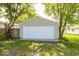 A detached one car garage with white door and green siding is shaded by mature trees at 3220 Newton Ave, Indianapolis, IN 46201