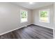 This is a simple bedroom featuring hardwood floors, base trim and two windows letting in natural light at 3614 N Whittier Pl, Indianapolis, IN 46218