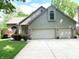 Charming home with a two-car garage, brick accents, a well-manicured lawn, and beautiful landscaping at 3819 S Village Dr, New Palestine, IN 46163