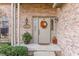 Inviting front entrance with brick wall, fall wreath, seasonal decorations, and lush greenery at 3819 S Village Dr, New Palestine, IN 46163