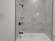 Bright bathroom featuring a shower-tub combo with marble-look tile and black fixtures at 4230 Kingsley Dr, Indianapolis, IN 46205