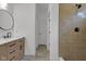 Bathroom with a tiled shower and a wood vanity topped with a round mirror and dark fixtures at 4234 Kingsley Dr, Indianapolis, IN 46205