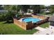 Backyard pool with surrounding wooden deck, landscaping, and green grass at 4625 Woodcrest Dr, Columbus, IN 47203