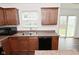 Kitchen with dark wood cabinetry, stainless steel sink, black dishwasher, and slider window above countertop at 5151 Climbing Rose Pl, Indianapolis, IN 46254