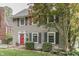 Inviting home exterior with a red front door, gray siding, well-maintained landscaping, and mature trees at 5306 N Kenwood Ave, Indianapolis, IN 46208
