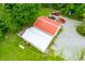 An aerial view of a house with a red metal roof, gravel driveway, and surrounding trees on a large, beautiful lot at 5858 N West Shore Dr, Morgantown, IN 46160