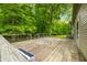 View of home's large wooden deck with rails, stairs and access to a grassy lot, surrounded by trees at 5858 N West Shore Dr, Morgantown, IN 46160