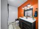 Bathroom including wood grain vinyl floors, decorative mirror, orange accent wall, and black fixtures at 5858 N West Shore Dr, Morgantown, IN 46160
