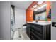 Well lit bathroom featuring a black vanity, orange accent wall, and white countertops at 5858 N West Shore Dr, Morgantown, IN 46160