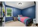 Bedroom in blue with matching bedspread, a side table, and a window with green view at 5858 N West Shore Dr, Morgantown, IN 46160