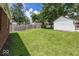 Spacious backyard featuring a lush lawn and privacy fence with mature trees at 6005 Winthrop Ave, Indianapolis, IN 46220