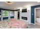 Bright bedroom with modern fireplace, wall-mounted TV, accent wall, large windows, and adjoining bathroom at 615 E Stop 11 Rd, Indianapolis, IN 46227