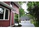 Charming home with a red woodgrain exterior and a detached garage in a lush, green setting at 625 E 57Th St, Indianapolis, IN 46220