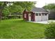 Detached garage with white doors and trim, set against a backdrop of green grass and trees at 625 E 57Th St, Indianapolis, IN 46220