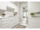 Bright kitchenette featuring white cabinets and stainless steel sink; view to a sunny living room at 6307 Keeneland Ct, Indianapolis, IN 46278