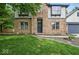 Close up view of a brick home's front entrance and garage, surrounded by a green lawn and small garden at 6396 Granny Smith Ln, Avon, IN 46123