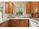 Kitchen sink and window with wooded view, light countertop and wooden cabinets at 6396 Granny Smith Ln, Avon, IN 46123