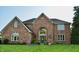 Charming brick home featuring an arched entry and beautifully landscaped front lawn with colorful flower beds at 6862 Riverside Way, Fishers, IN 46038