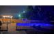 A backyard pool at night illuminated with blue lighting, surrounded by a fence and patio furniture at 7935 N County Road 650 E, Brownsburg, IN 46112