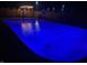 Backyard pool illuminated in blue at night, featuring a basketball hoop and fenced patio area at 7935 N County Road 650 E, Brownsburg, IN 46112