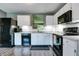 Modern kitchen featuring white cabinets, black appliances, subway tile backsplash, and wood grain vinyl flooring at 7942 Dillon Pl, Indianapolis, IN 46236