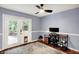 Well-lit office with a ceiling fan, modern desk, and wood floors leading to an outdoor patio through a pet door at 9302 Budd Run Dr, Indianapolis, IN 46250