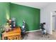 Bedroom features an olive green wall, work desk, exercise bike, and neutral-toned carpet at 938 N Tuxedo St, Indianapolis, IN 46201