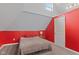 Bedroom with red accent wall, neutral carpet, a bed with gray blankets, and a window allowing natural light at 938 N Tuxedo St, Indianapolis, IN 46201