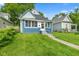 Quaint home features an inviting front porch, well-maintained lawn and mature trees at 938 N Tuxedo St, Indianapolis, IN 46201