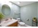 Bathroom features a round mirror, a toilet, and a vanity with neutral countertops and plants at 101 Meadowview Dr, Mooresville, IN 46158