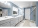 Bathroom with double sink, window, blue walls, tile floor, and glass door at 1026 Woodglen Dr, Westfield, IN 46074