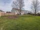 Large backyard with lush green grass, a wooden fence, patio, and chairs, perfect for outdoor enjoyment at 10443 Ringtail Pl, Fishers, IN 46038