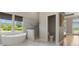 Bright bathroom featuring a soaking tub, a glass shower, and backyard views at 10655 E 200 S, Zionsville, IN 46077