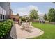 Backyard with stone patio, outdoor seating, and playhouse on a manicured lawn at 10962 Stoneleigh Dr, Noblesville, IN 46060