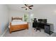 Bright bedroom with a wooden bed frame, desk, ceiling fan, and windows providing natural light and outdoor views at 10962 Stoneleigh Dr, Noblesville, IN 46060