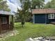 View of backyard showcasing a small storage shed, grassy area, and the exterior of the blue home at 1206 Mcdougal St, Indianapolis, IN 46203