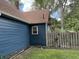 View of the side of a blue house with an external spiral staircase, a fenced yard, and leafy trees at 1206 Mcdougal St, Indianapolis, IN 46203