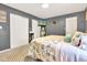 This main bedroom has gray walls, plush carpet, a patterned quilt, and ample closet space at 12121 East 21St St, Indianapolis, IN 46229
