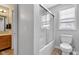Bathroom featuring a shower-tub combo with glass doors, toilet, and vanity with wood cabinets at 13766 Heatherfield Dr, Fishers, IN 46038