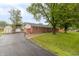 Exterior view of brick ranch home with green lawn, large trees, and a detached garage at 1514 Bittersweet Dr, Greenfield, IN 46140