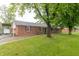Ranch-style brick home featuring a green lawn, large trees, and driveway at 1514 Bittersweet Dr, Greenfield, IN 46140
