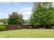 Large backyard with a lush lawn, mature trees, and a charming fire pit area with Adirondack chairs at 15409 Heath Cir, Westfield, IN 46074