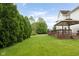 Side yard view showcasing a well-manicured lawn, privacy hedges, deck, and gazebo at 15409 Heath Cir, Westfield, IN 46074